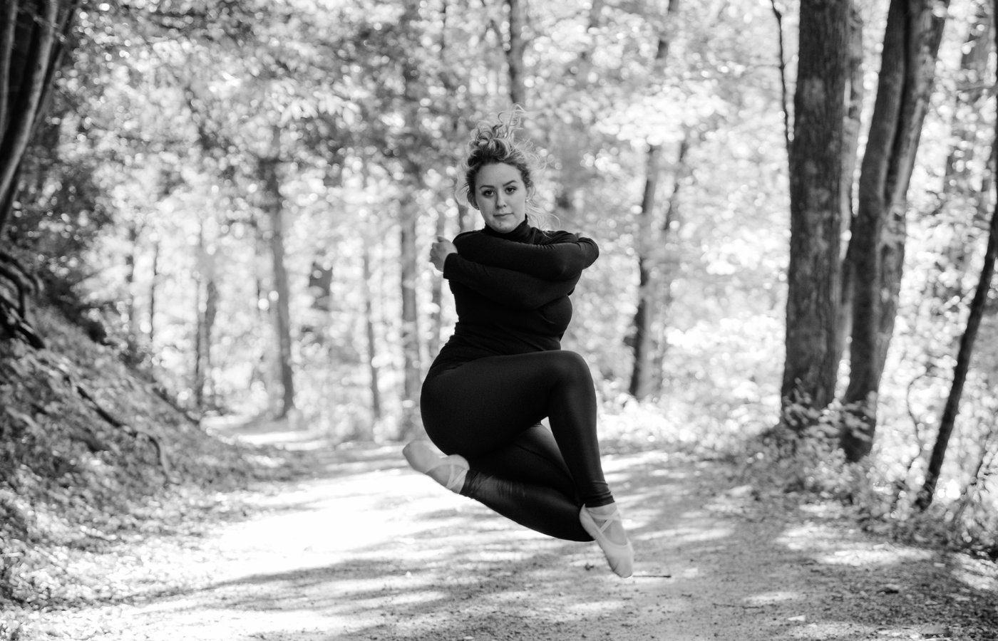 Dancer in mid-leap on forest path